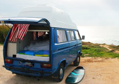 Blue campervan in front beach in surf holidays