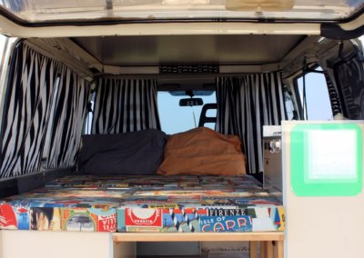 Big bed inside campervan to rest after surf day