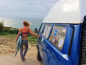 Girl appreciate beach view next to campervan in surf holidays