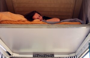 Girl takes a nap in big bed inside campervan