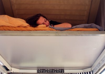 Girl takes a nap in big bed inside campervan