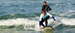 Surfer learns how to surf on the surf lesson with surf instructor