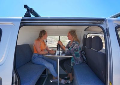 Two travelers enjoying a conversation inside a Ginginha campervan from Atlantic Coast Campers, Portugal