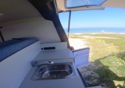 View from inside an Atlantic Coast Campers van overlooking a beach in Portugal, perfect for surf enthusiasts and campervan travel.